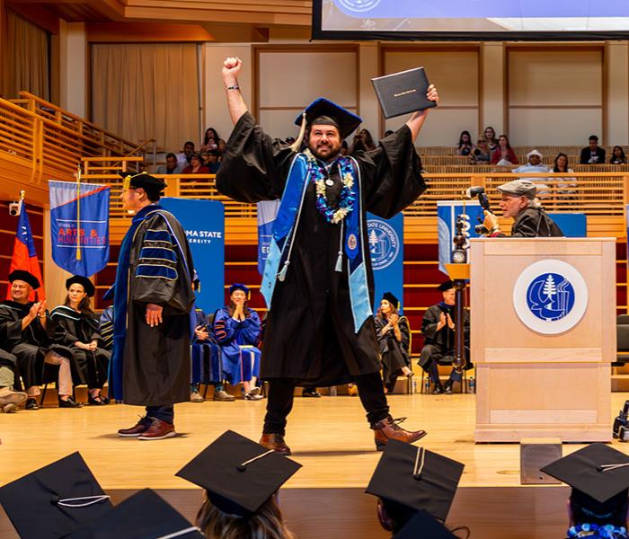 Graduate raises hands with diploma