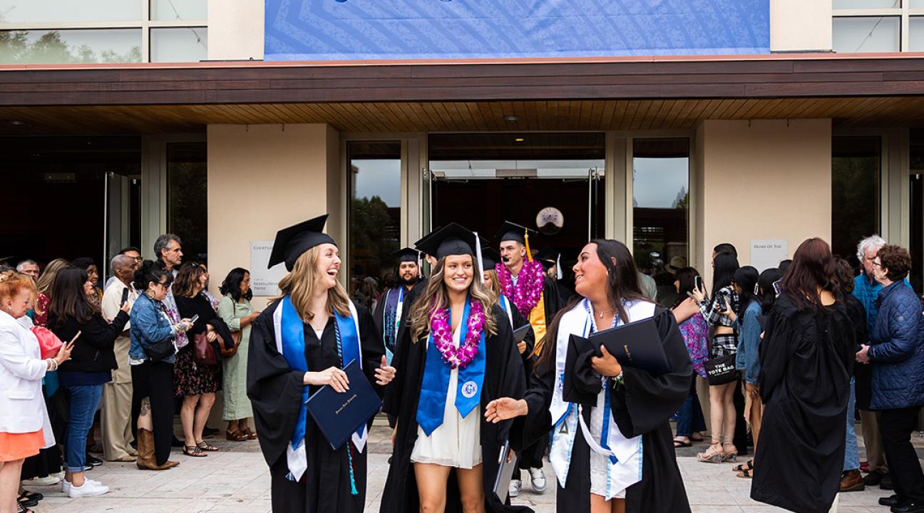 Three graduates walk outside