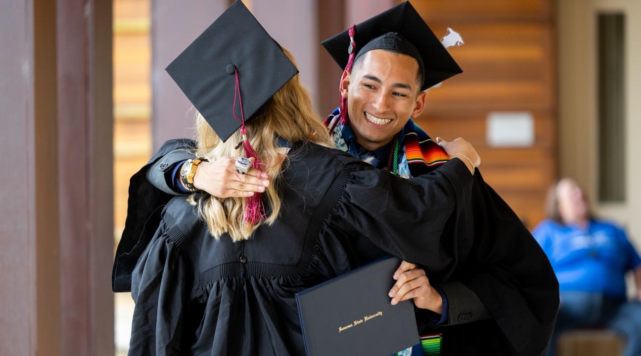 Two grads hugging