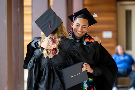 Two grads hugging